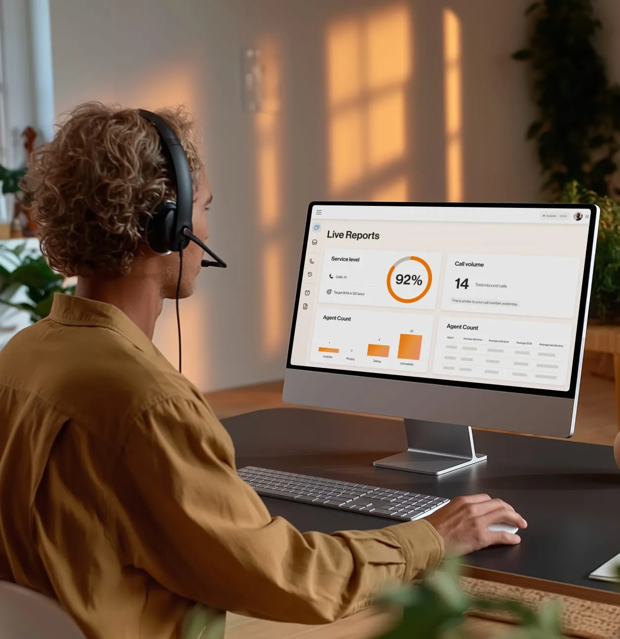 Professional using a headset and viewing live reports on service levels and call volume on a computer screen in an office setting.