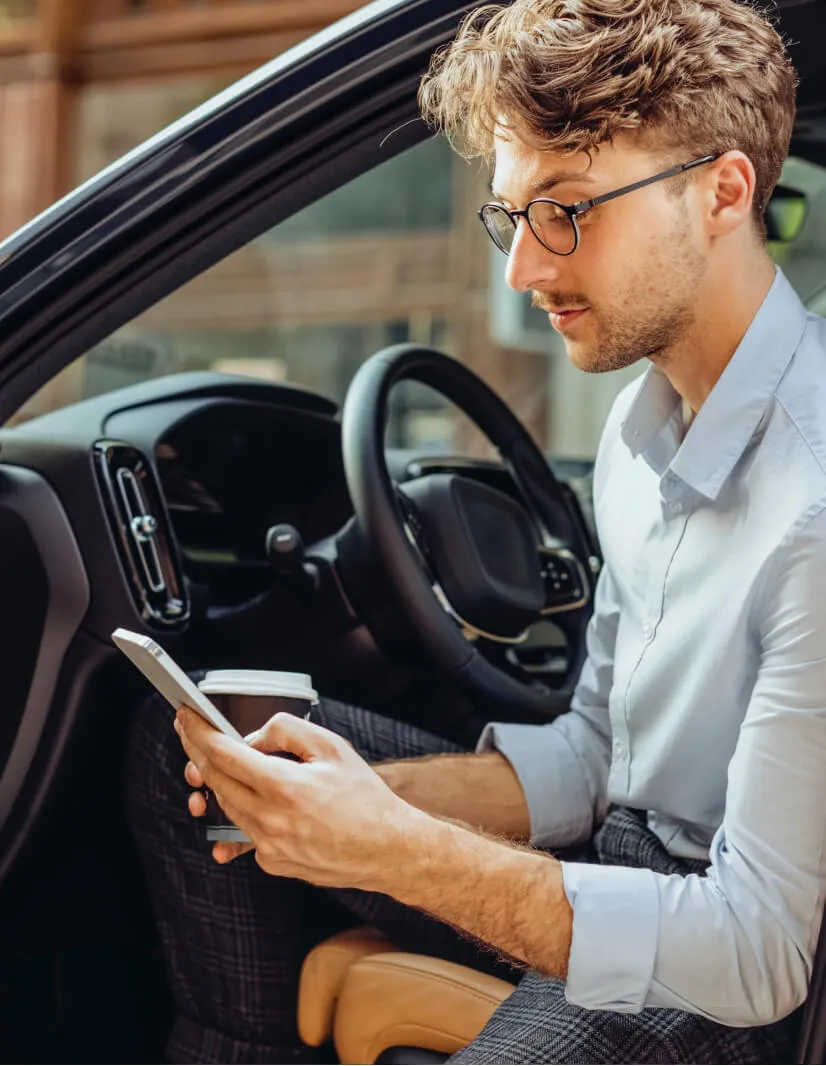 A man working on his phone in a parked car