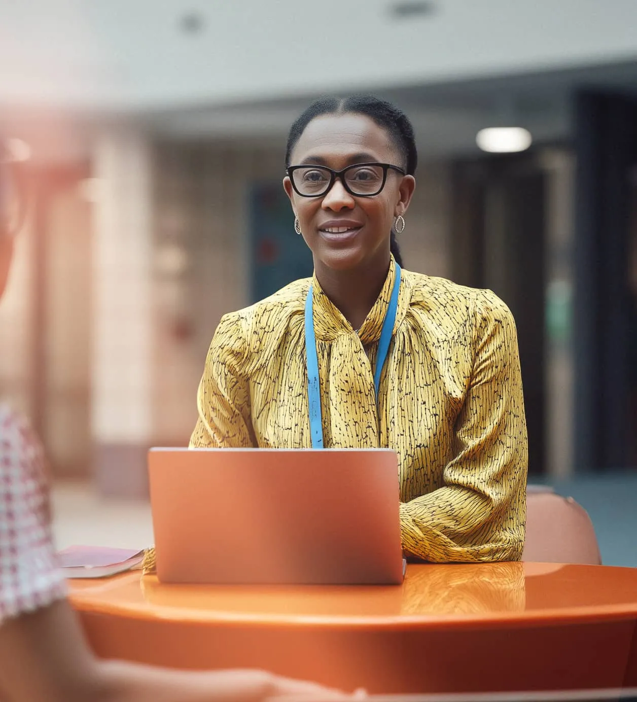 A woman smiles as she speaks to someone while sat behind her laptop.