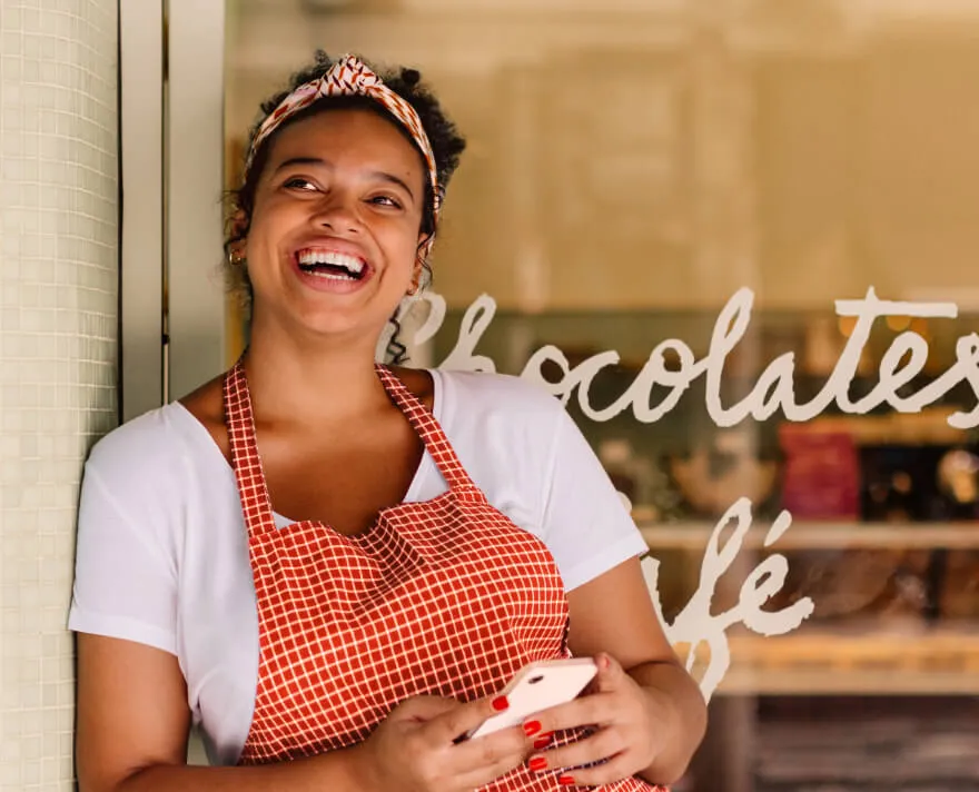 A female cafe owner smiling in front of her shop