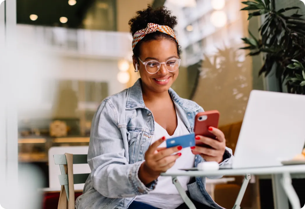A man sitting on a porch, casually using a cell phone while enjoying the outdoor setting.