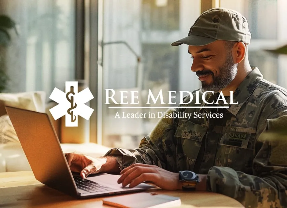 A man in military camouflage and a cap smiles while typing on a laptop in a bright indoor setting.